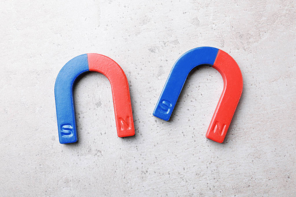 Red and blue horseshoe magnets on grey background, top view - Foto, imagen