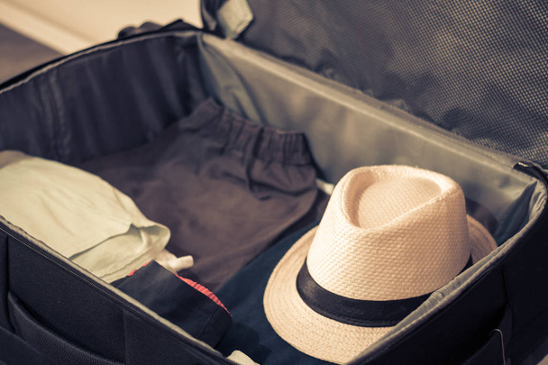 Open travel bag with clothes and hat - Photo, Image