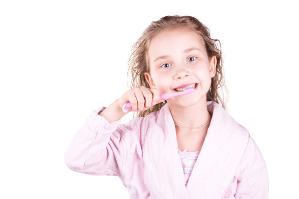 Beautiful happy smiling little girl brushing her teeth after bath, shower - Фото, изображение