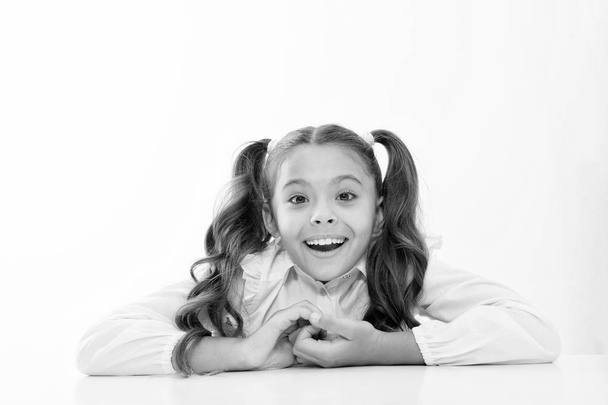 Excellent pupil lean on desk isolated white. Perfect schoolgirl with tidy fancy hair. School hairstyle ultimate top list. Prepare kid first school day. Schoolgirl happy smile cute ponytail hairstyle - Fotografie, Obrázek