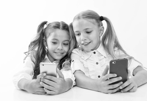 Online life concept. Schoolgirls cute pupils use smartphones big diagonal screen to check social networks. Check it out. Send message to friend. Online communication messaging. Game application - Фото, зображення