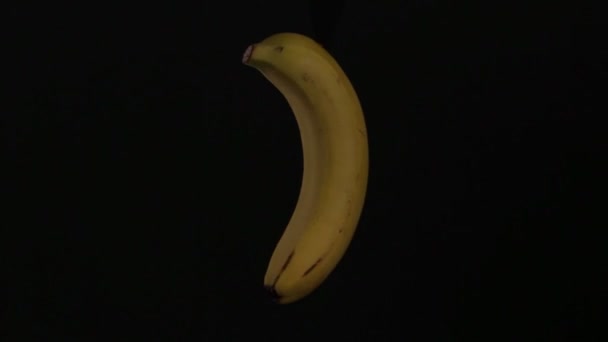 plátano amarillo está girando sobre un fondo negro en aislamiento
 - Metraje, vídeo