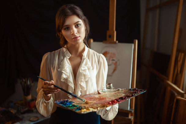 Female painter drawing with color palette and brush in studio. Creative paintbrush art, workshop interior on background - Photo, Image