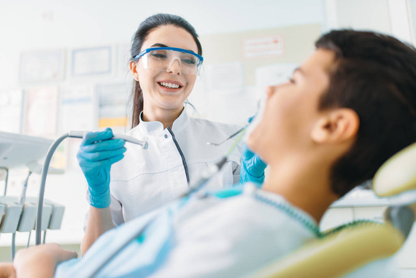 Seal installation process, pediatric dentistry, children stomatology. Female dentist drilling teeth, dental clinic - Photo, Image