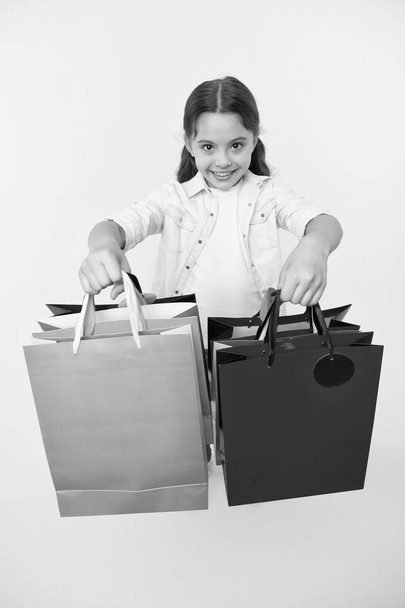 Check out her shopping packages. Girl carries shopping bags yellow background. Girl fond of shopping. Child cute shopaholic with bunch shopping bags black friday total sale. Take shopping packages - Foto, Bild