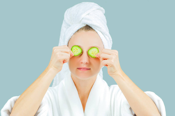 Skin care. Facial beauty treatment. Beautiful woman with perfect fresh skin face andcucumbers on eyes - Foto, Imagen