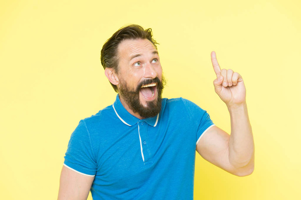 Fresh idea concept. Handsome smiling mature man keeping finger raised and looking upwards while standing against yellow background. Man bearded cheerful fresh idea. Birth of ideas. Idea gesture - Foto, Imagem