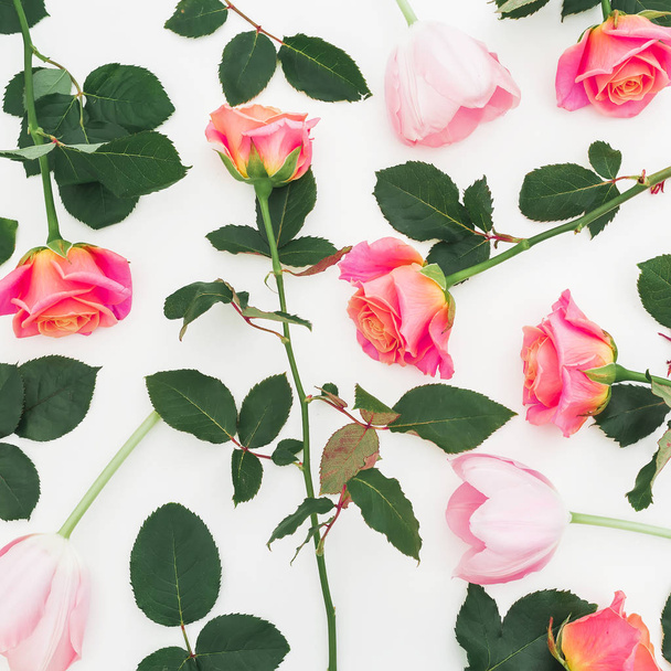 Λουλουδάτο μοτίβο με τριαντάφυλλα λουλούδια και πράσινα φύλλα σε άσπρο φόντο. Επίπεδη lay, κορυφαία θέα. Λουλούδια πλαίσιο - Φωτογραφία, εικόνα