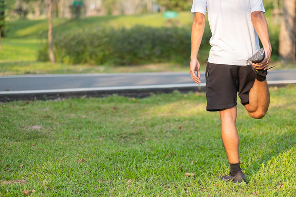 Young athlete man streching in the park outdoor. male runner warm up ready for jogging on the road outside. asian Fitness walking and exercise on footpath in morning. wellness and sport concepts - Photo, image