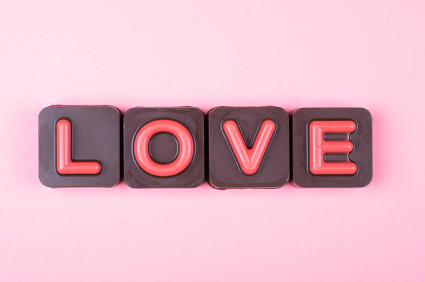 Love engraved in chocolate on colored background - Photo, Image