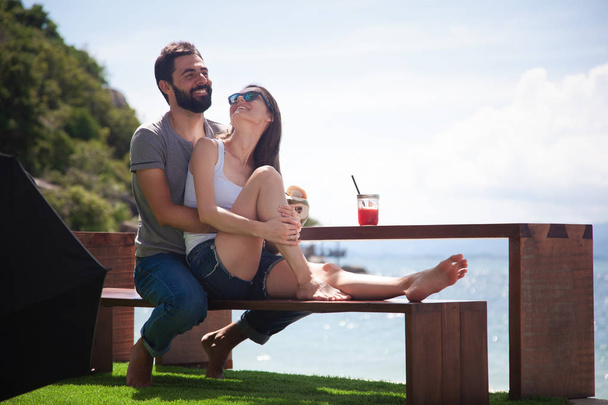 Joven hermosa pareja enamorada en el mar tropical, en la cafetería de la playa durante unas vacaciones de luna de miel, el Día de San Valentín. Concepto de amor. Viaje a la isla
 - Foto, Imagen