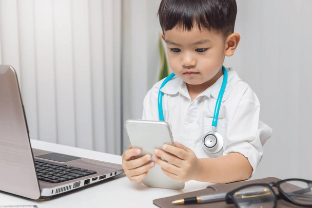 Young asian boy playing doctor and using computer laptop. - Fotografie, Obrázek