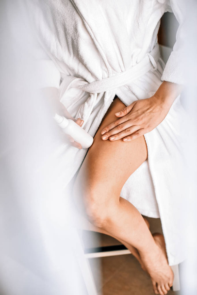 Cuidado corporal. Una joven en el baño se aplica crema natural en las piernas. Contra las venas varicosas y edema de piernas
 - Foto, Imagen