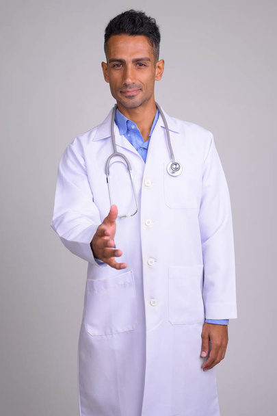 Portrait of young happy Persian man doctor giving handshake - Photo, Image