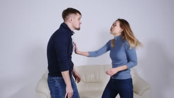 Het concept van huiselijk geweld. Een man slaat een jonge vrouw thuis. - Video