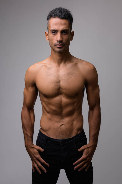 Studioaufnahme eines jungen muskulösen Mannes ohne Hemd vor weißem Hintergrund - Foto, Bild