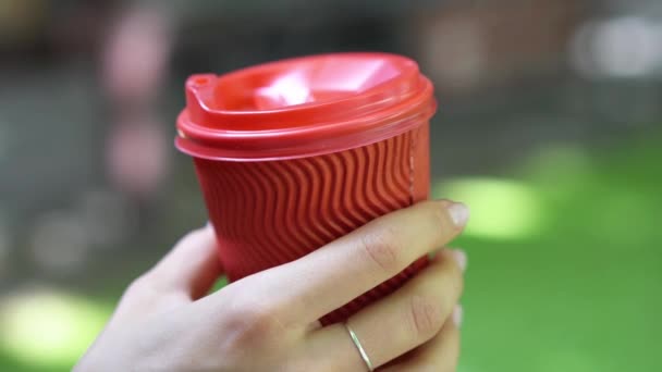 Женщина на улице держит красную пластиковую чашку в руке
. - Кадры, видео