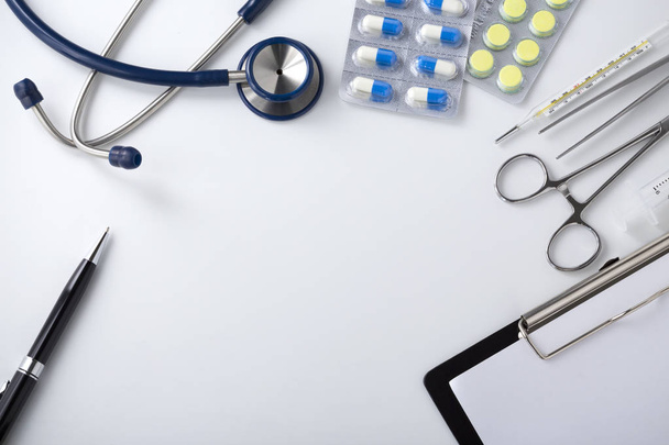 Lääkärin työpöytä lääketieteellisillä työkaluilla ja pillereillä, ylhäältä
 - Valokuva, kuva