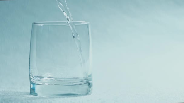 Water pour into a glass on a white background - Felvétel, videó