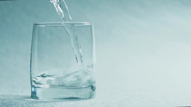 Water pour into a glass on a white background - Filmati, video