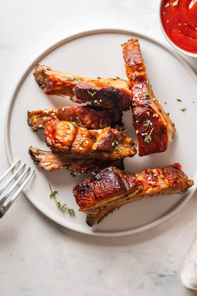 Bbq pork ribs with chili sauce on white plate. Pork ribs on slate background. Copy space. - Foto, Imagen