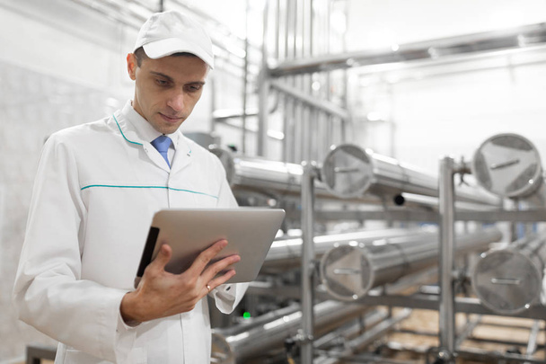 Süt fabrikasında onun elinde bir tablet ile teknoloji uzmanı - Fotoğraf, Görsel