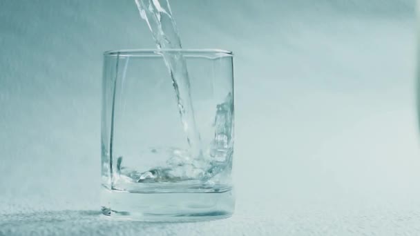 Νερό ρίξτε σε ένα ποτήρι σε λευκό φόντο - Πλάνα, βίντεο