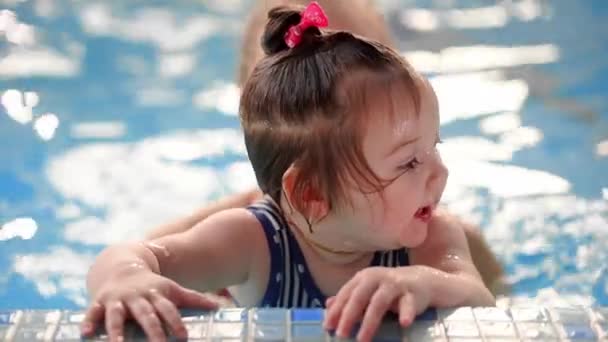 Bambina mentre nuota in piscina guardando la fotocamera in piedi sul lato in acqua e sorridendo
 - Filmati, video