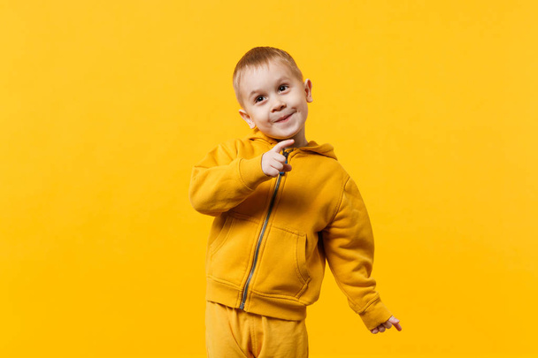 kleine niedliche Kind Junge 3-4 Jahre alt tragen gelbe Kleidung isoliert auf leuchtend orangefarbenem Hintergrund, Kinder Studio Porträt. Menschen aufrichtige Emotionen, kindlicher Lebensstil Konzept. Attrappe Kopierraum - Foto, Bild