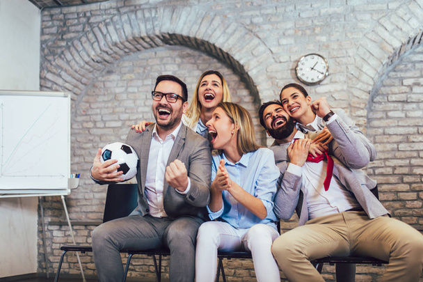 Happy business people or football fans watching soccer on tv and celebrating victory. Friendship, sports and entertainment concept. - Foto, imagen