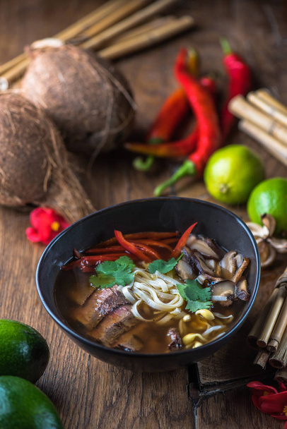 Vietnamese  Pho soup in black bowl on wooden table - Foto, afbeelding