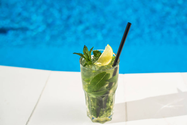 closeup of mojito cocktail in glass placed on poolside - Foto, Imagen