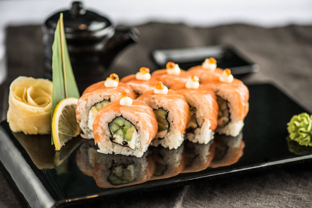 Japanese sushi roll served on black platter - Foto, afbeelding