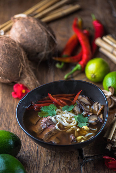 Vietnamese  Pho soup in black bowl on wooden table - Фото, изображение