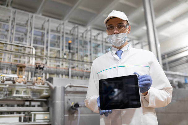 tecnólogo muestra una pantalla en blanco de la tableta en la planta láctea
 - Foto, imagen