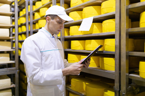 inspector toma notas en la hoja en el almacén de queso
 - Foto, imagen