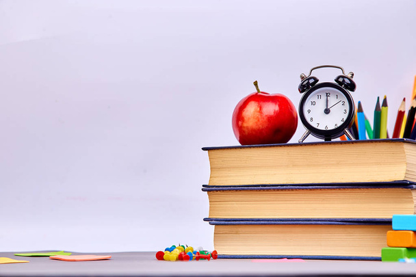 Okula dönüş sağlar. Kitap ve yeşil zemin üzerine kırmızı elma. Çalar saat ile natürmort. Kopya alanı. - Fotoğraf, Görsel