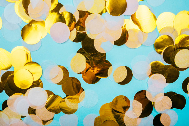 Levendige gouden confetti op pastel blauwe achtergrond. Feestelijke ontwerp. - Foto, afbeelding