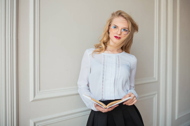 stylish young business woman in fashion eyeglasses posing with book indoors - 写真・画像
