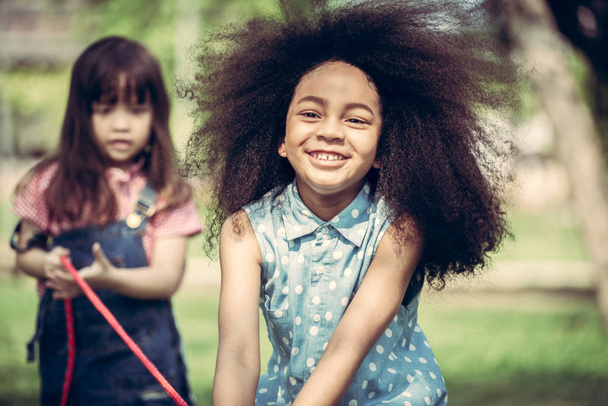 Szczęśliwe dzieci gry przeciąganie liny i zabawy podczas Letnich camping w parku. Koncepcja wypoczynku dzieci. - Zdjęcie, obraz