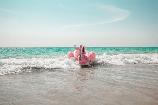 Man is having fun on pink flamingo inflatable pool float - Photo, image