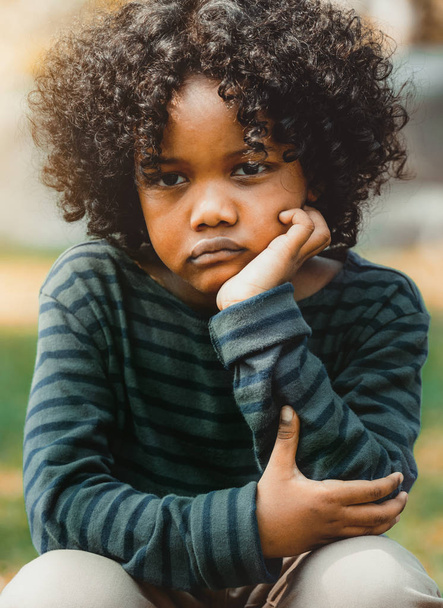 不満はほとんどアフリカ系アメリカ人の子供が公園で座って退屈。少年: 表示中の否定的な感情。子供の障害の概念. - 写真・画像