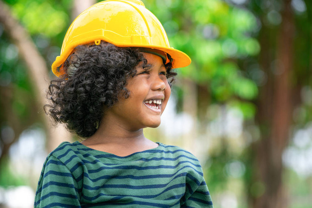 Feliz niño ingeniero con casco de seguridad amarillo casco duro y riendo con felicidad. Concepto de educación y aprendizaje
. - Foto, Imagen