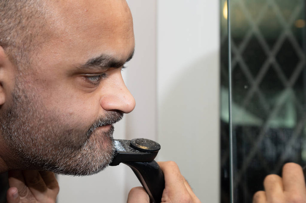 Britânico Asiático homem, aparando seu restolho ou barba na frente do espelho
. - Foto, Imagem