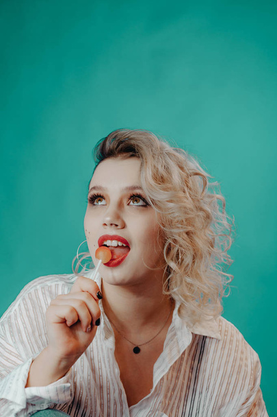 Girl with red lips and freckles, licks lollipop - Φωτογραφία, εικόνα