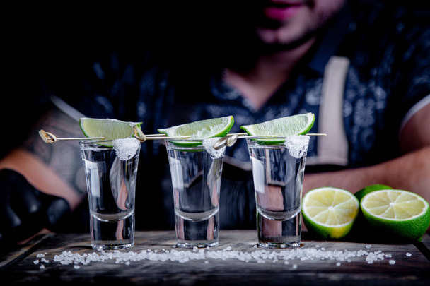 aperitivo con amigos en el bar, tres vasos de alcohol con lima y sal para decorar. Tequila shots, enfoque selectivo
 - Foto, imagen