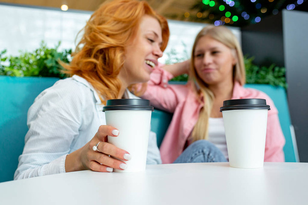 Two beautiful female friend sit in a cafe after their purchases during sales - Foto, Imagen