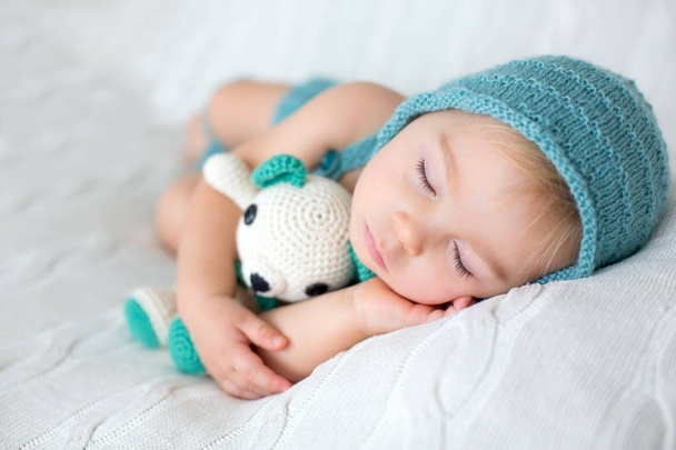 Sweet toddler boy, sleeping with teddy bear toy, cute knitted outfit, isolated - Фото, зображення