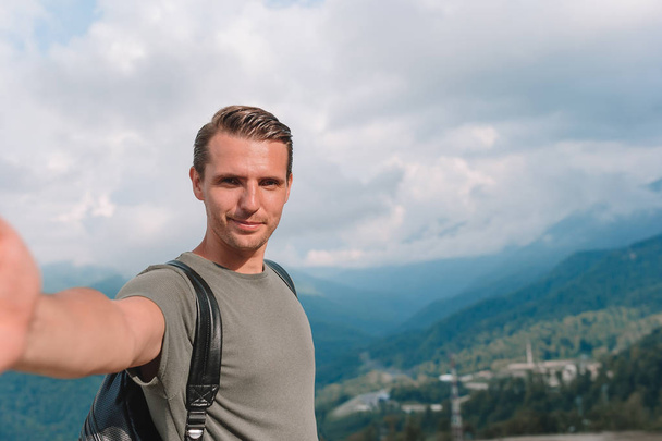 Man tourist taking selfie in mountains outdoors - 写真・画像