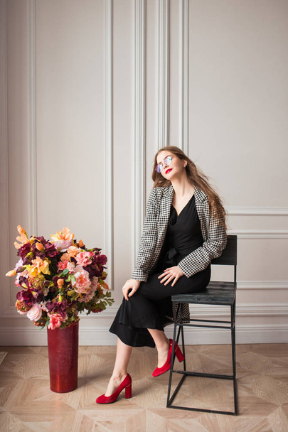 modelo de moda elegante jovem em óculos com jaqueta de couro posando em poltrona
 - Foto, Imagem